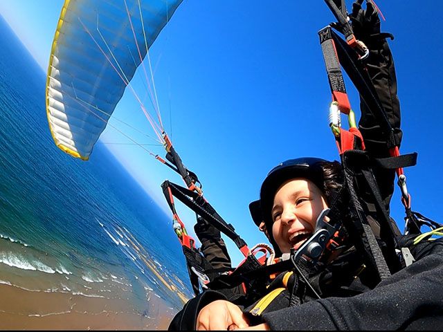 Niño disfrutando de su vuelo en parapente biplaza en Sopela